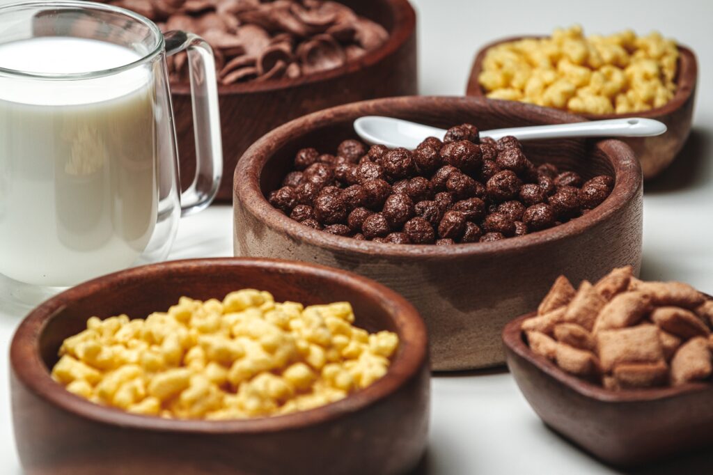 Bowls with different sorts of breakfast cereal products and glas
